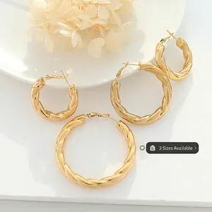 French style gold-plated twisted hoop earrings in three sizes on white stone background