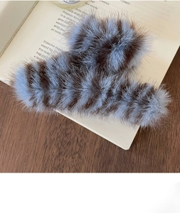 Detail of blue and brown striped faux fur hair claw clip resting on an open book
