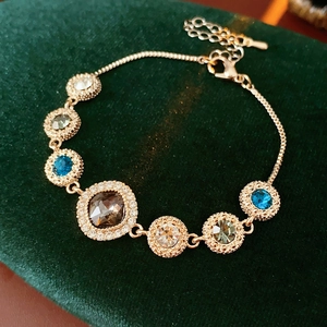 Close-up of golden rhinestone bracelet with multicolor crystals on green velvet