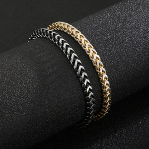 Titanium steel wheat chain bracelet for men in gold and gun black finish on display