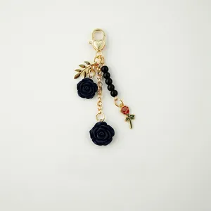 Detailed view of the dark blue resin rose keychain with golden leaf and black beads