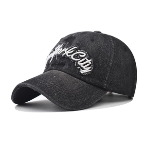 Detailed view of white New York City embroidery on washed black denim baseball cap