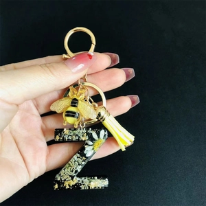 Detail of resin letter Z keychain featuring real dried white flowers and gold foil flakes