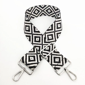 Detail of adjustable black and white geometric woven bag strap with silver metal swivel hooks
