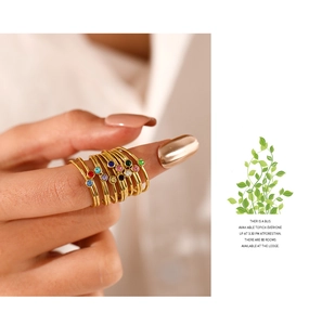 Detail of minimalist gold rings with colorful single rhinestones on a woman's hand