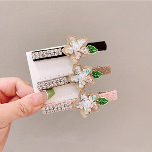 Detailed view of three floral hair clips with rhinestones and faux pearls in three colors