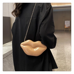 Lip-shaped nude crossbody bag with gold chain strap shown on model for size perspective