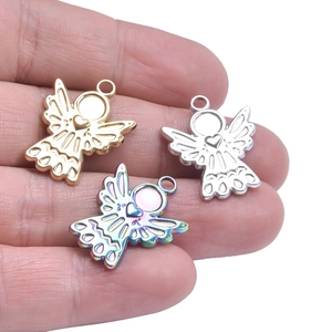 Three tiny angel wing heart pendants in gold, silver and rainbow colors held by hand
