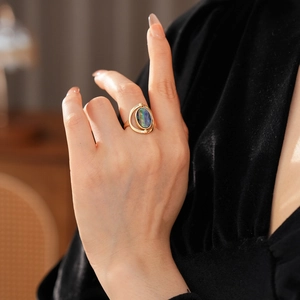 Detailed shot of vintage gold shell ring with oval blue gemstone on hand