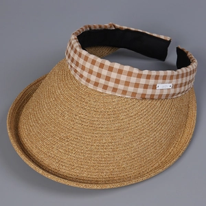Detail of the woven straw sun hat with brown gingham fabric edge and a side decorative label
