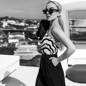 Detail eines One-Shoulder-Tops mit 3D-Blume und schwarz-weißem Wellenmuster-Design