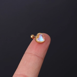Macro shot of a tiny heart-shaped ear stud with opal inlay on a finger for size