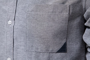 Detailed macro view of Oxford fabric texture and button sewing on grey casual shirt