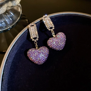 Elegant purple heart drop earrings with pavé crystals on a black velvet jewelry tray