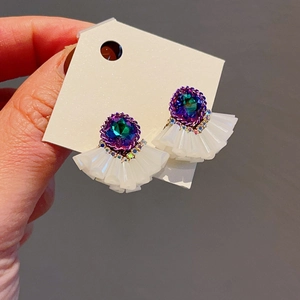 Detail of luxury fan-shaped earrings with gradient crystals and white pleated texture