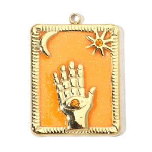 Detail of gold rectangular Hamsa hand pendant with orange enamel and celestial motifs