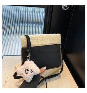 Détail du sac seau en daim noir avec bordure en laine d'agneau beige et breloque ours