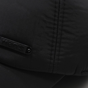 Close-up of black men's winter cap showing textured fabric and embossed metal tag
