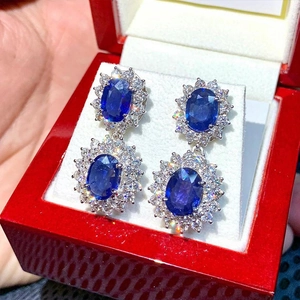 Dettagli di orecchini di zaffiro con pietre blu ovali e aloni di diamanti bianchi