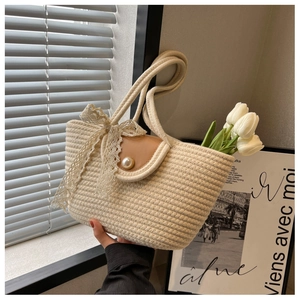 Detail of straw woven tote bag with brown flap, large pearl buckle and lace ribbon