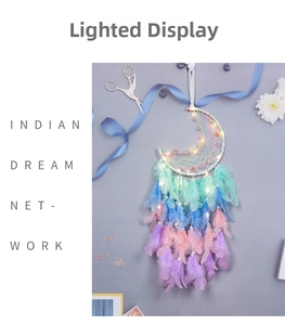 Macro shot of moon-shaped dream catcher with warm LED lights and colorful feathers
