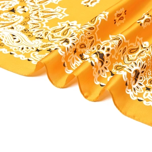 Close-up of yellow paisley print silk scarf showing satin texture and draping folds