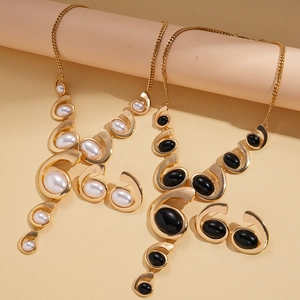 Gold metal necklace set with white pearls and black oval charms in a minimalist design