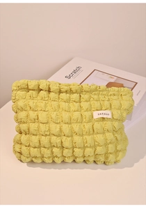 Primer plano de la bolsa de maquillaje amarilla de seersucker con textura de burbujas