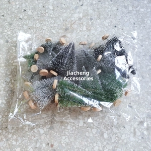 Assorted mini Christmas trees with snow spray effect and wooden bases in a clear package