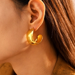 Polished gold C-shaped chunky hoop earrings on model with high gloss PVD plating