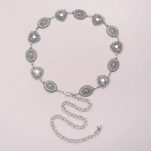 Detailed macro view of vintage silver metal waist chain with hollow heart and floral charms