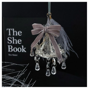Macro shot of chandelier glass ornament with grey velvet bow and soft feather details