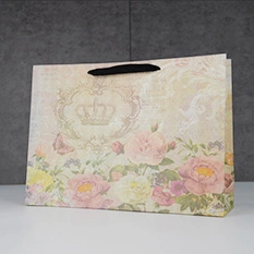 Detail showing vintage ivory paper gift bag with rose floral print and crown motif