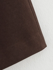 Macro view of brown twill fabric with precision stitching on a modern women's suit
