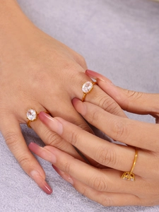 Detailed view of three gold rings with oval zircons on a model's hand for luxury styling