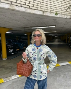 Détail d'une veste matelassée en coton blanc avec broderie florale bleue et taille nouée