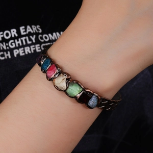 Vintage copper cuff bracelet featuring raw multi-color crystals worn on a wrist for women