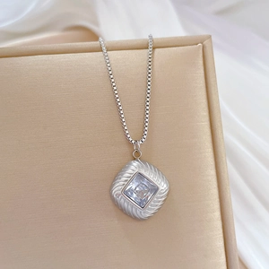 Detail of silver box chain necklace with square gemstone pendant in jewelry box