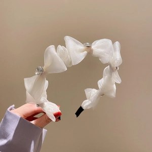 Detailed macro view of cream-white organza bow headband with sparkling central rhinestones