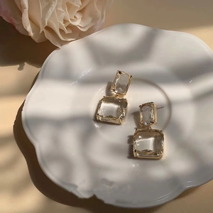 Elegant geometric earrings with transparent crystals and gold metal frames on floral plate
