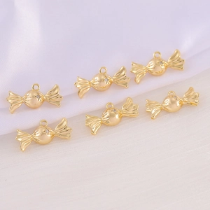 Golden candy-shaped metal charms for DIY jewelry making on white silk background