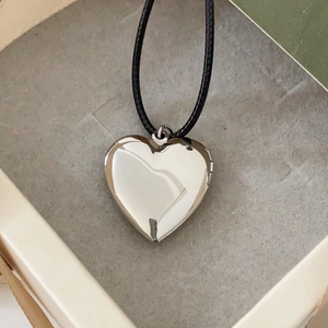 Close-up of polished heart-shaped floating locket pendant on a black rope necklace