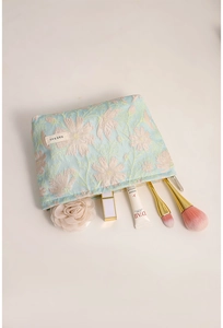 Dettaglio della borsa per trucco in jacquard floreale con pennelli e rossetti all'interno spazioso