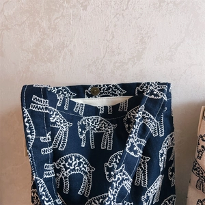 Close-up of magnetic buckle closure on navy canvas tote bag with white embroidery