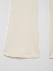 Détail de l'ourlet évasé sur un pantalon en maille crème pour femme élégante