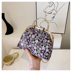 Detail of floral shell bag featuring gold metal handle and elegant chain strap