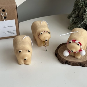 Detailed view of polar bear shaped candle with red scarf and bell on wooden base