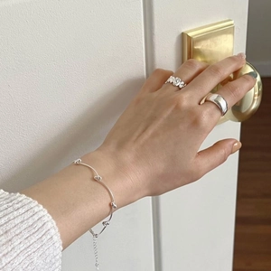 Close-up of minimalist S925 sterling silver irregular rings and beaded chain bracelet
