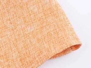 Gros plan sur la texture du tissu en tweed orange et blanc avec motif de tissage détaillé