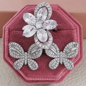 Macro detail of silver flower ring and butterfly earrings on a pink velvet jewelry box